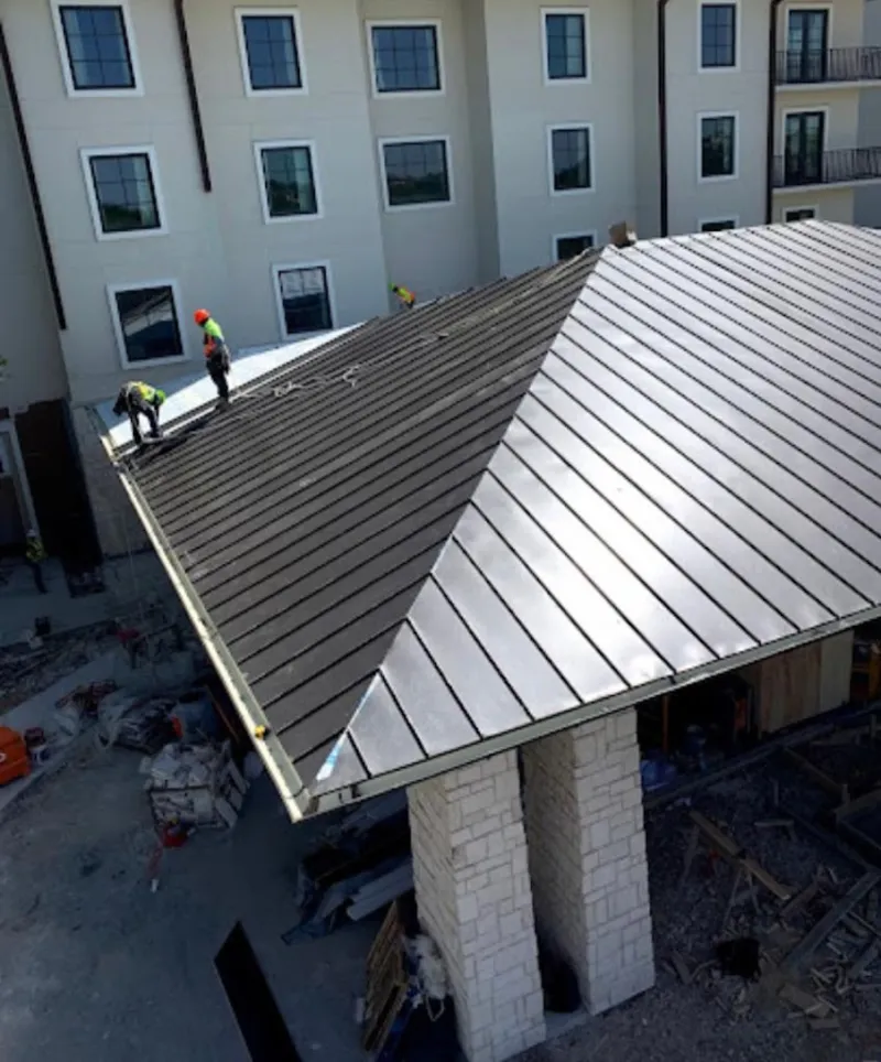 Crew installing standing seam metal roof panels on a commercial project in Oakley